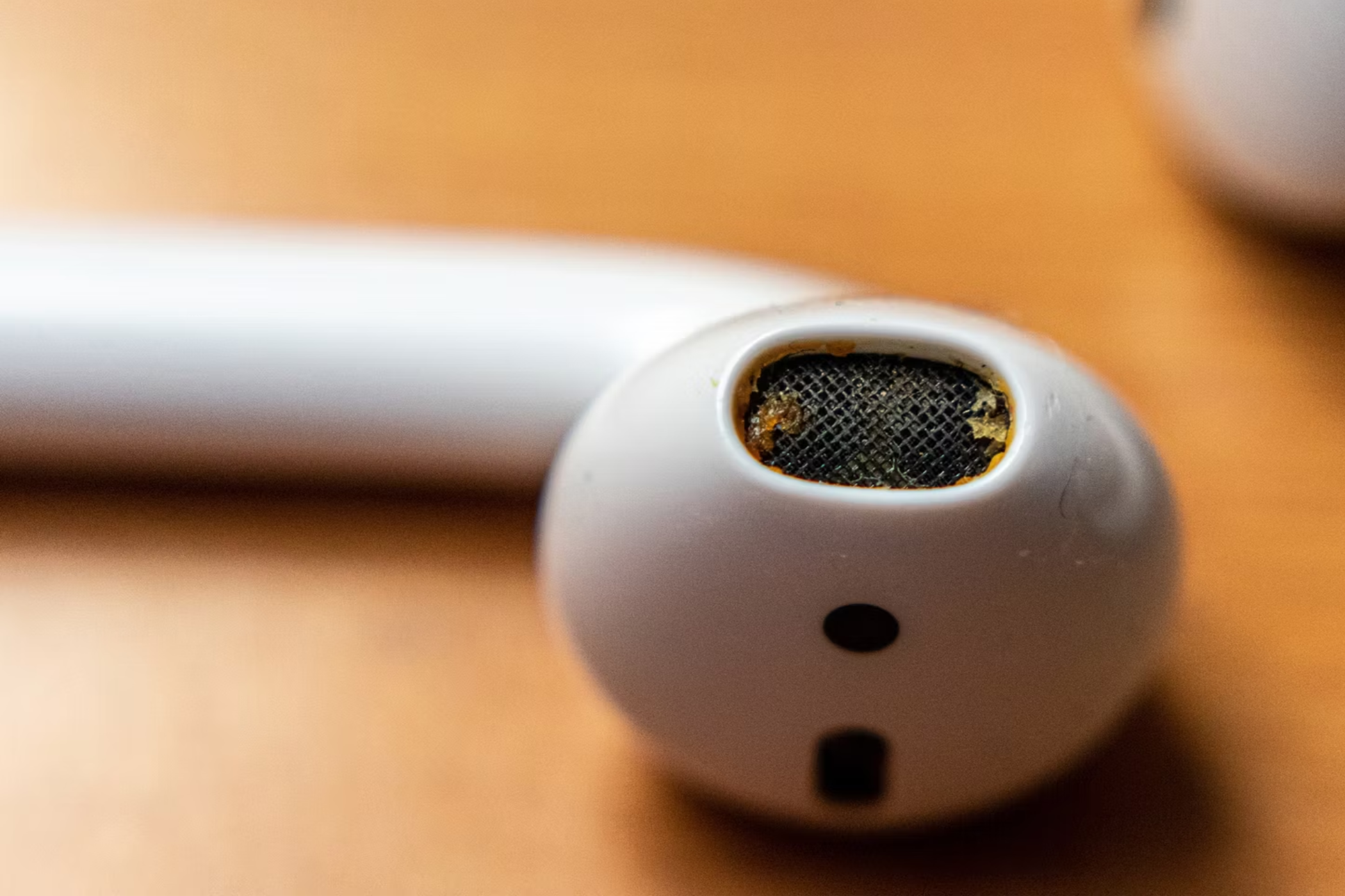 Основной акустический выход AirPods с накопившейся серой и грязью.