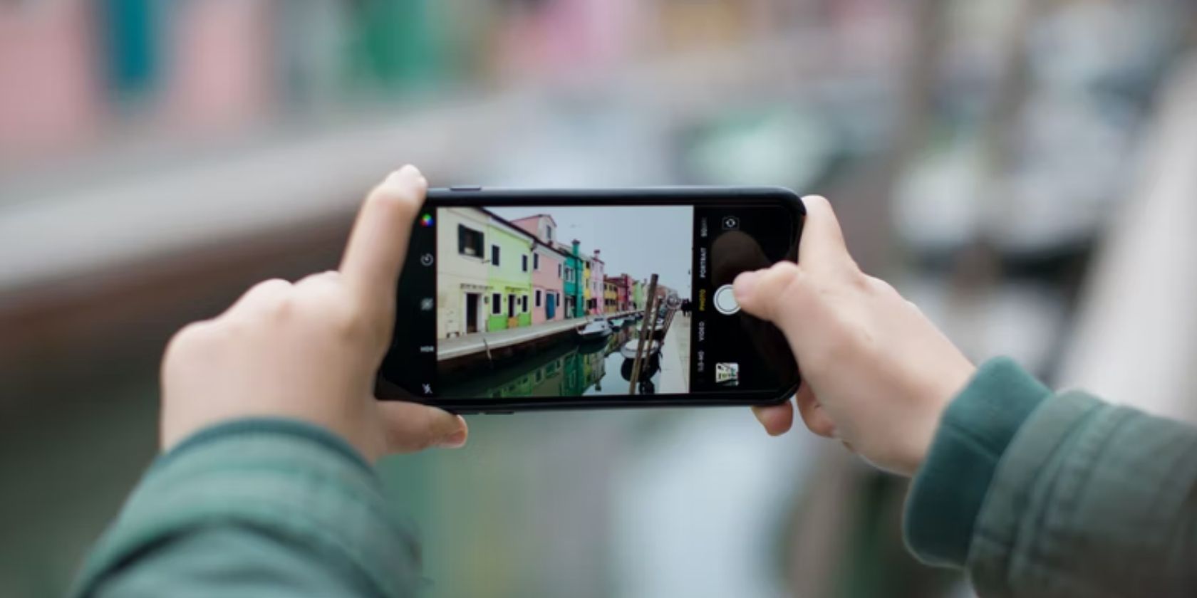 человек держит iPhone и фотографирует здания у канала