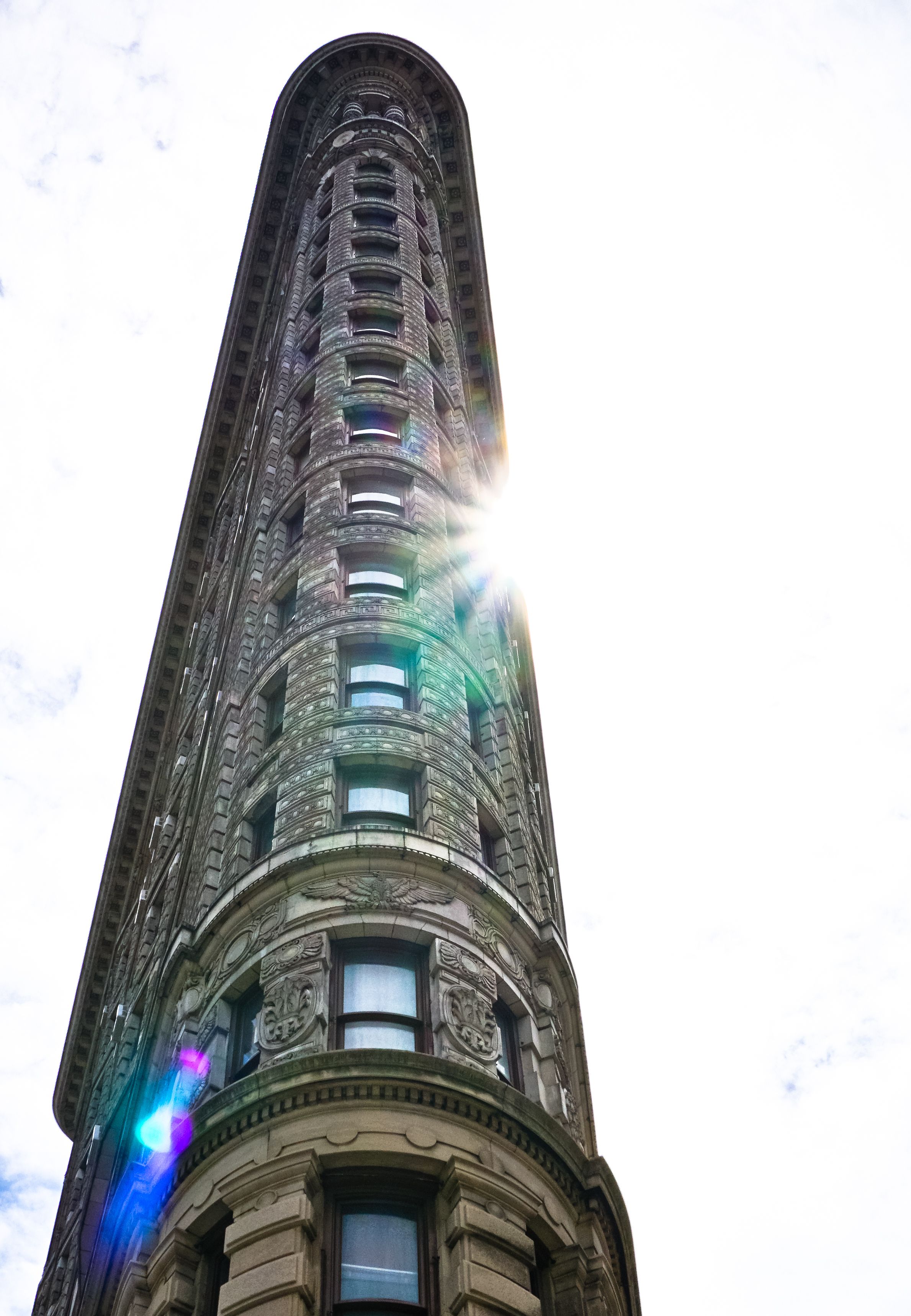 Солнце выглядывает из-за здания Flatiron в Нью-Йорке.