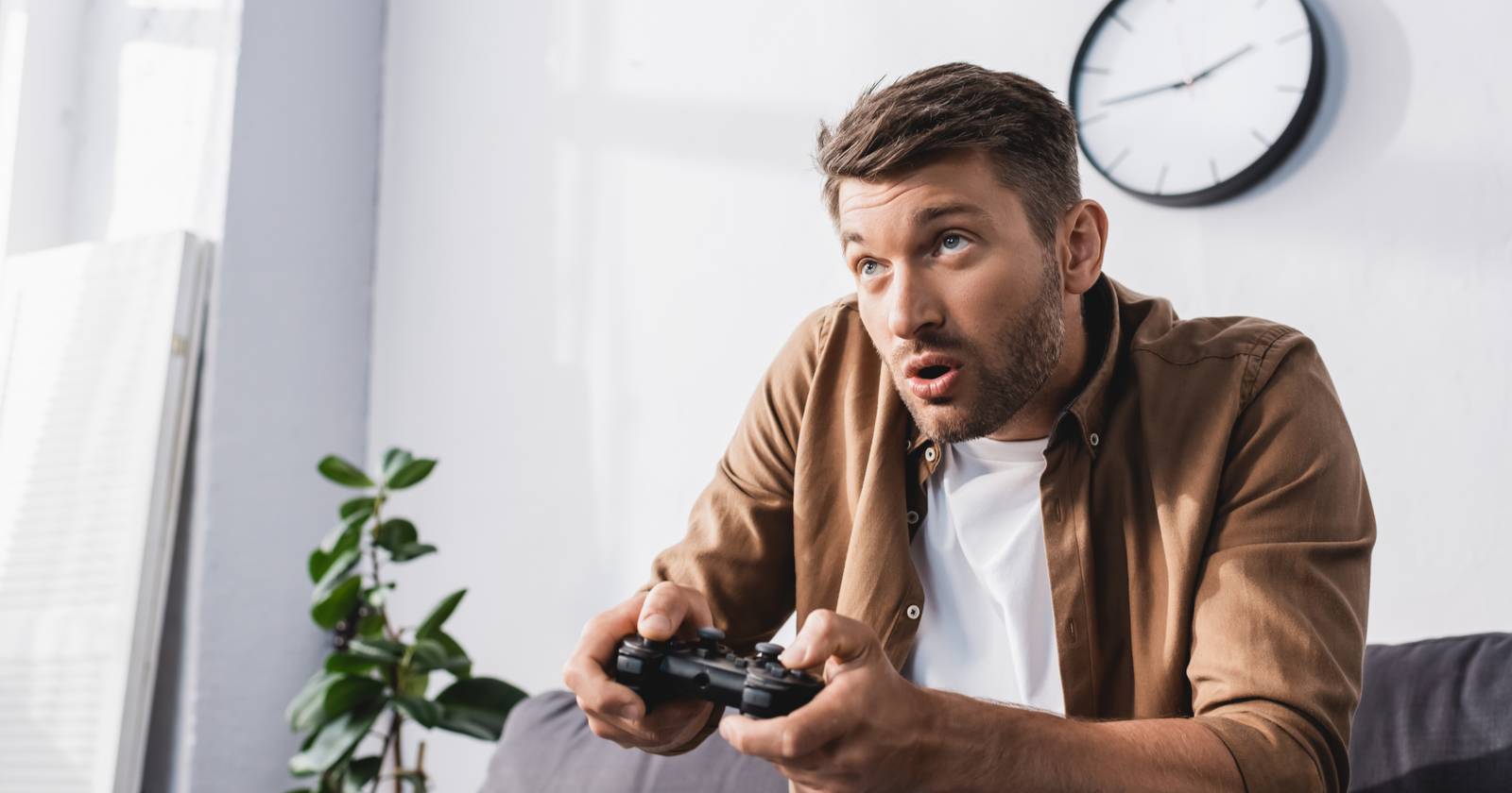 Мужчина держит контроллер PlayStation и увлечённо играет