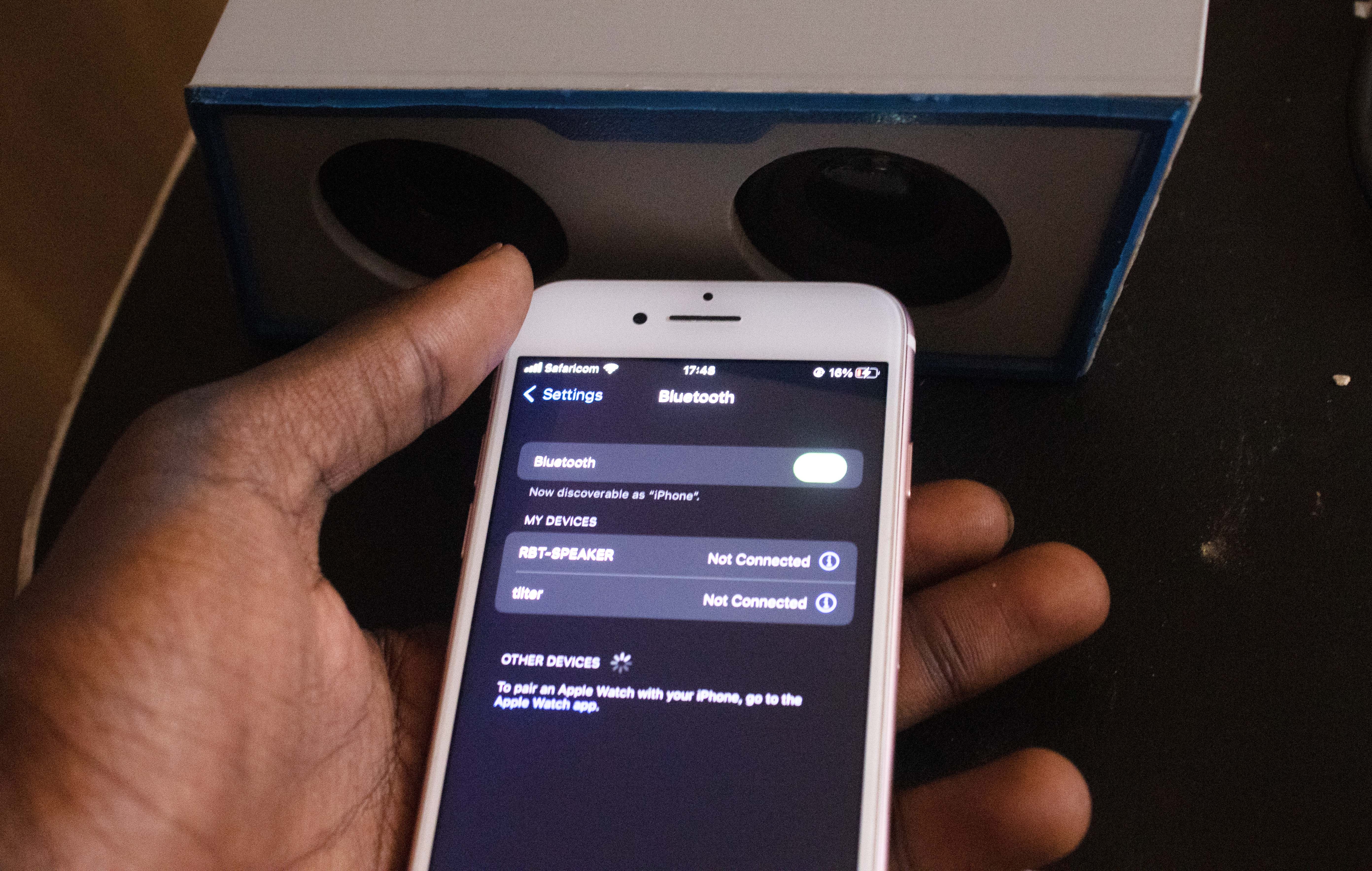 Рука держит iPhone с включённым Bluetooth