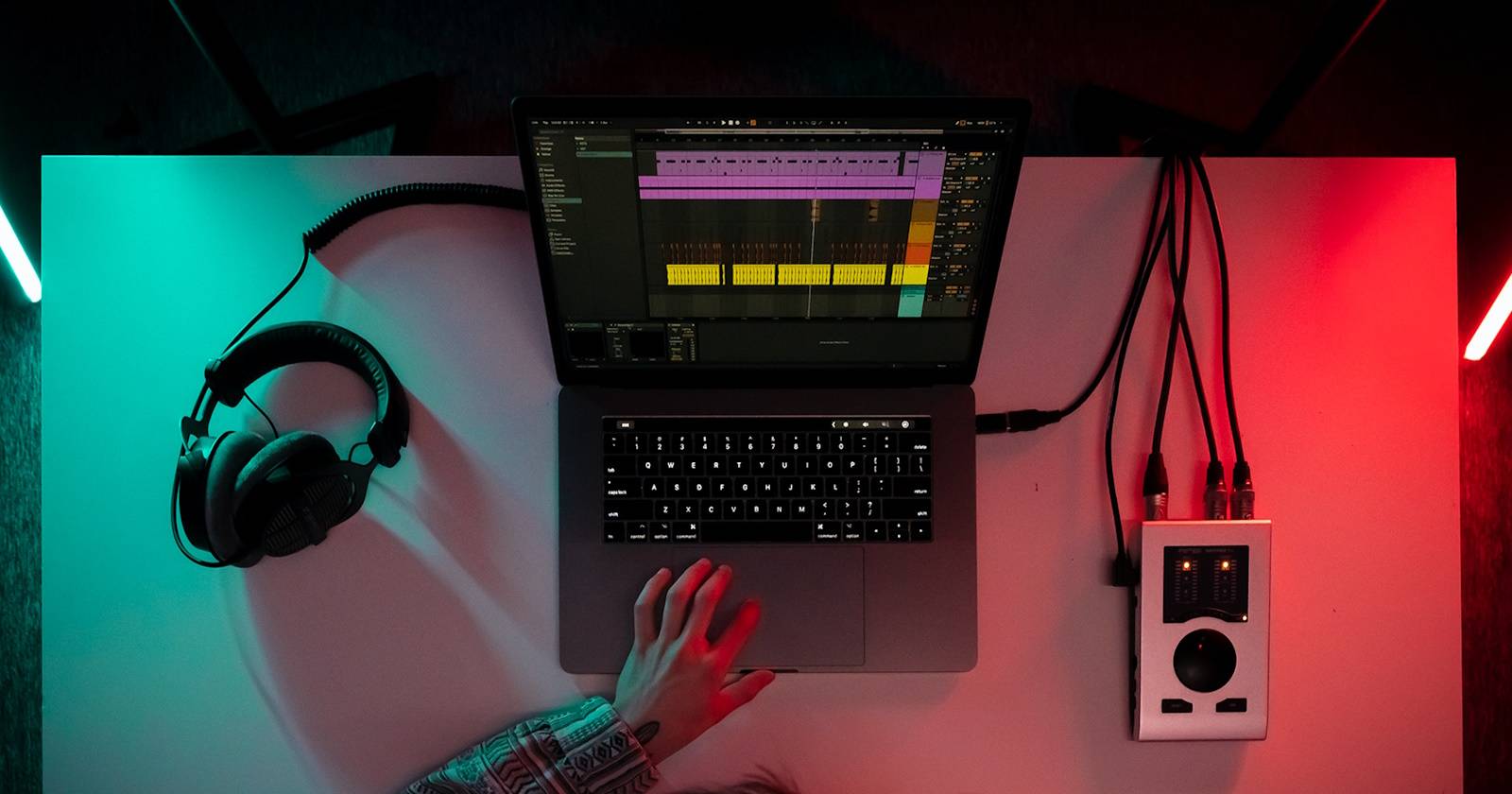 Рука тянется к ноутбуку с открытой DAW и проектом в REAPER