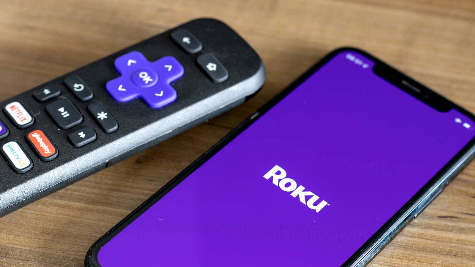 Пульт Roku на фоне смартфона с логотипом Roku