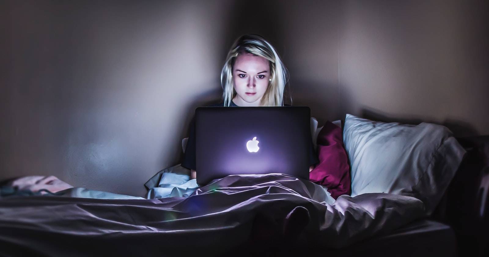 Девушка работает за компьютером в постели