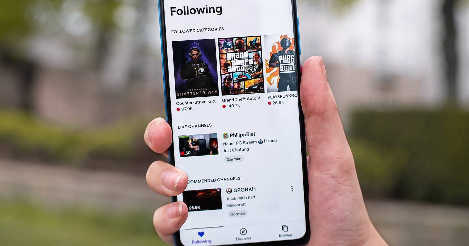 Человек держит телефон с открытым приложением Twitch
