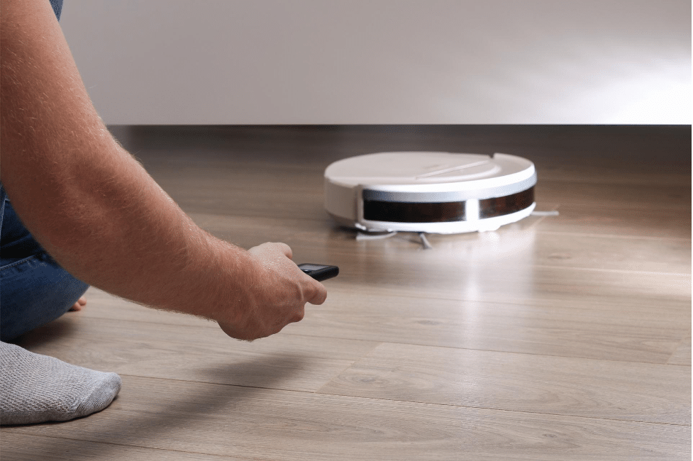 Robot aspirapolvere che pulisce vicino a un divano, confronto con aspirapolvere tradizionale