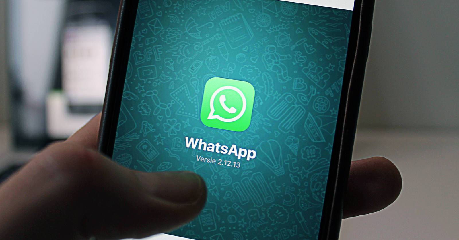 Человек держит смартфон с открытым приложением WhatsApp