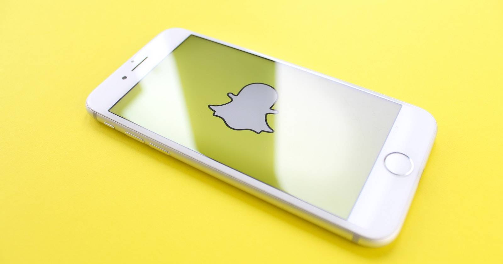 Телефон на экране блокировки Snapchat на жёлтом столе