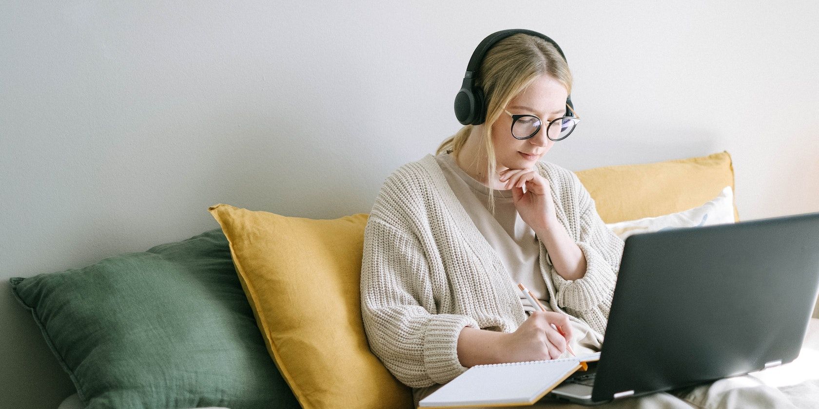 Lady sitting with a laptop and writing on a notebook