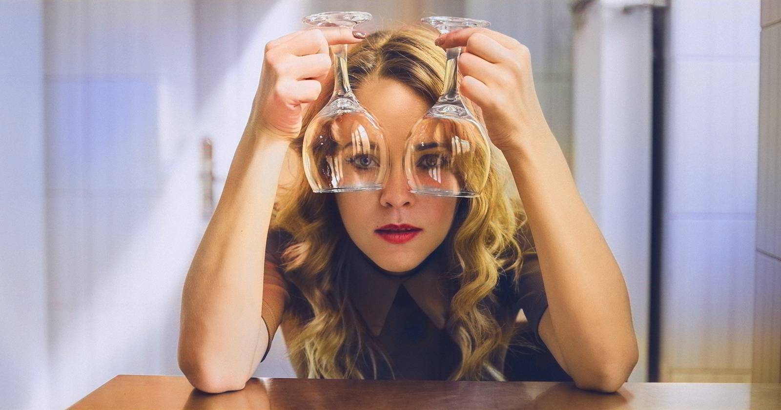 Женщина держит два бокала вина вверх ногами