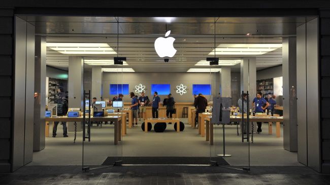Вид магазина Apple с витринами и сотрудниками.