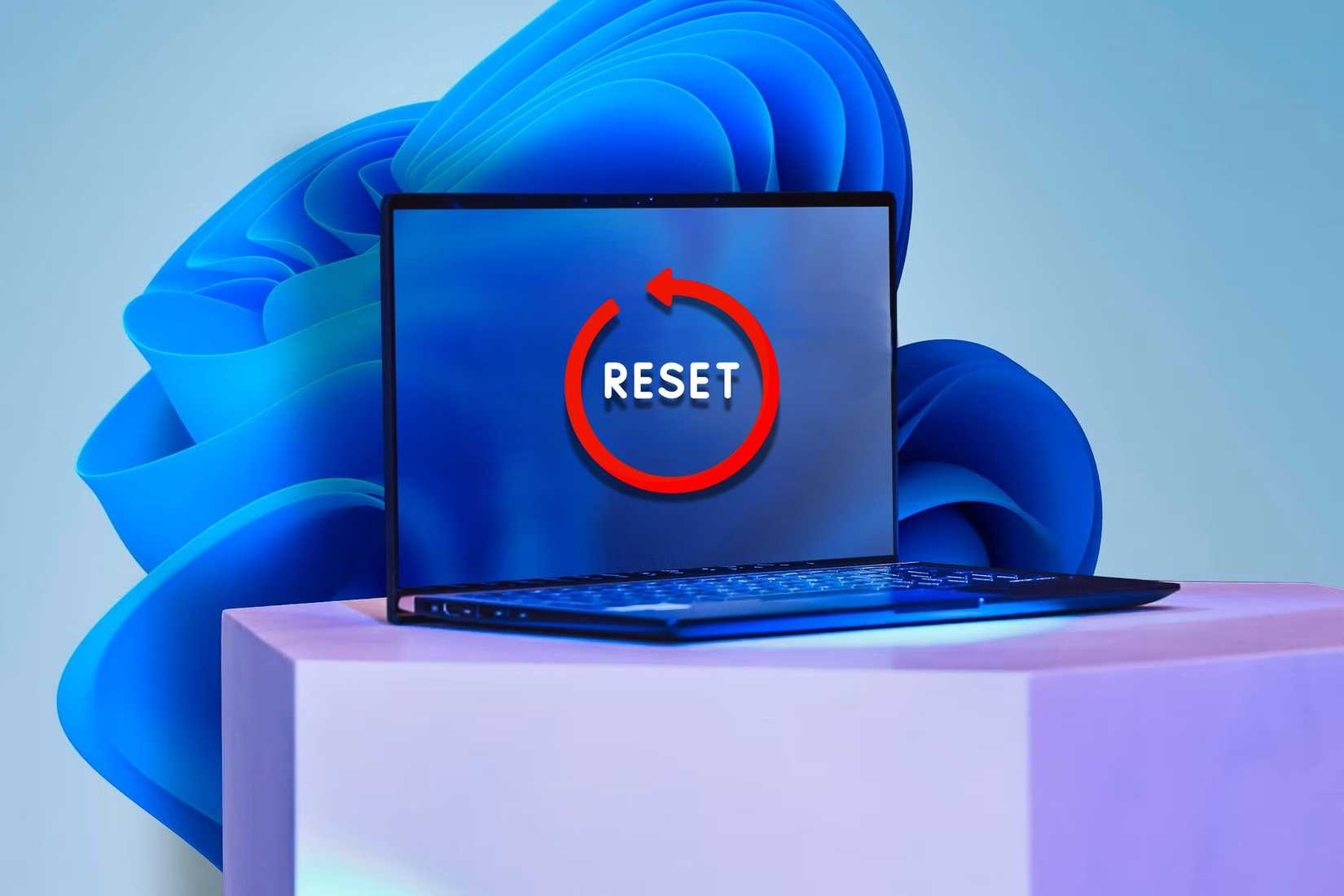 Ноутбук с наклейкой Reset на экране и обоями Windows 11 на заднем плане