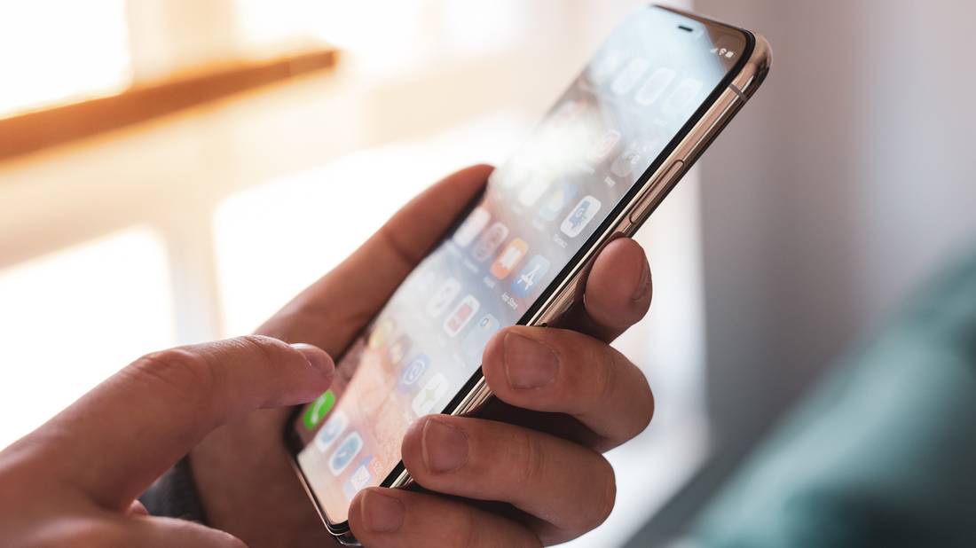 Человек прикасается к экрану iPhone