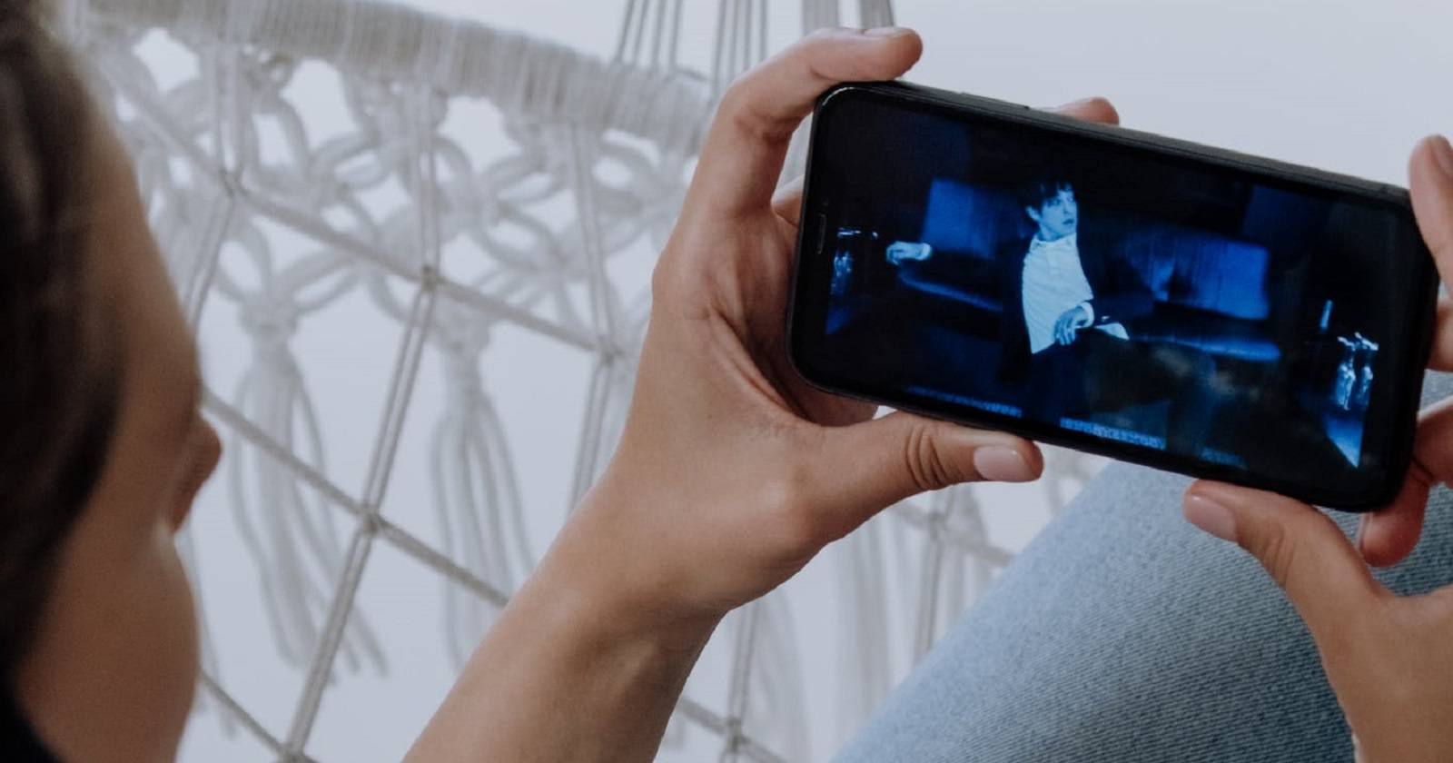 Человек воспроизводит видео на iPhone.