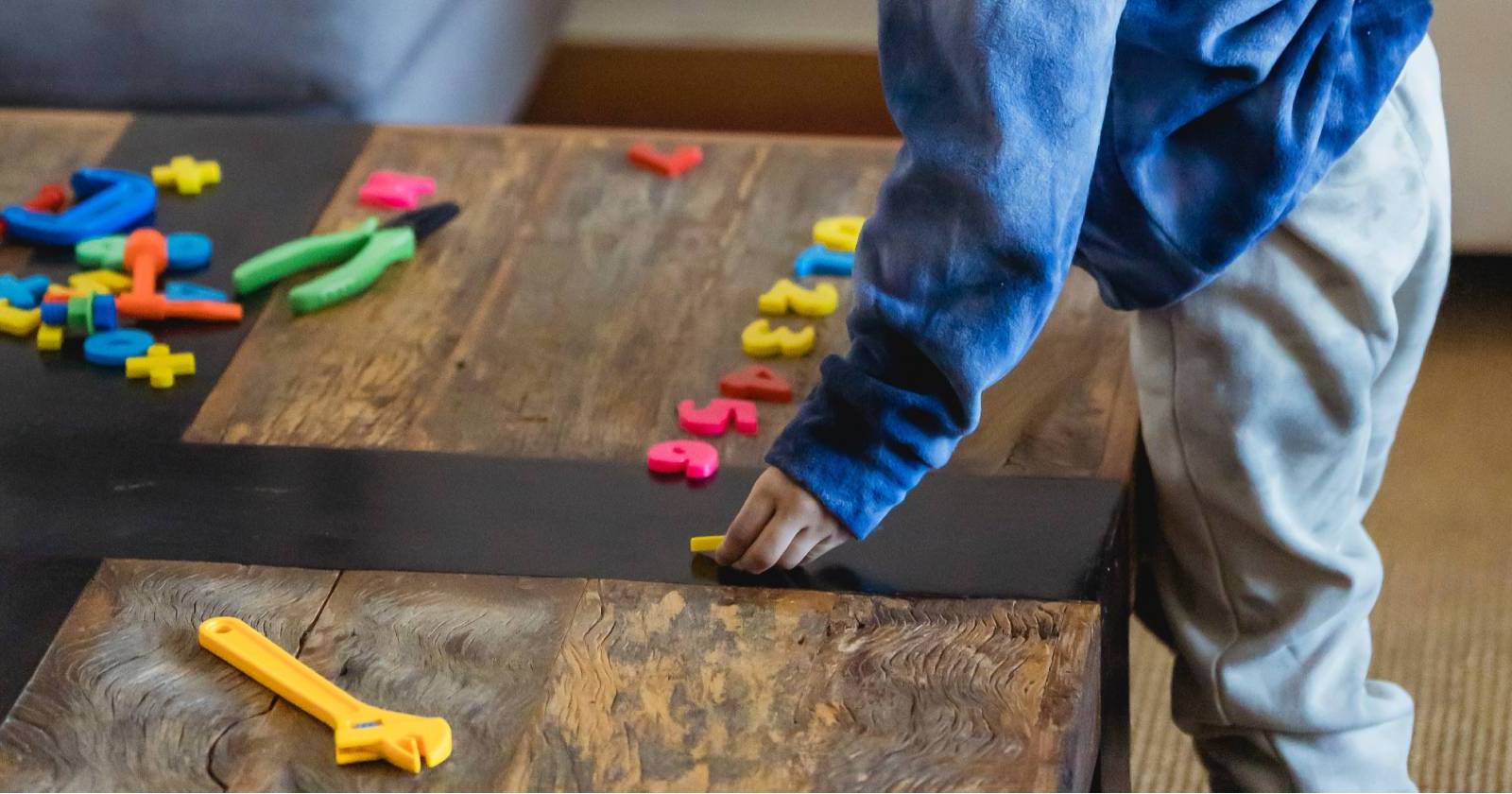 Ребёнок сортирует бумажные карточки с числами на столе