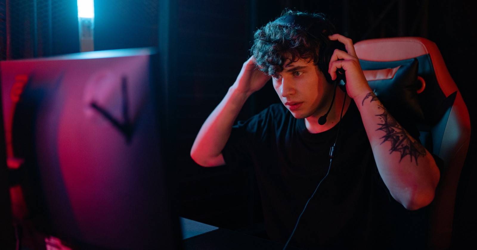 Человек за столом в наушниках играет в игры через облачный стриминг