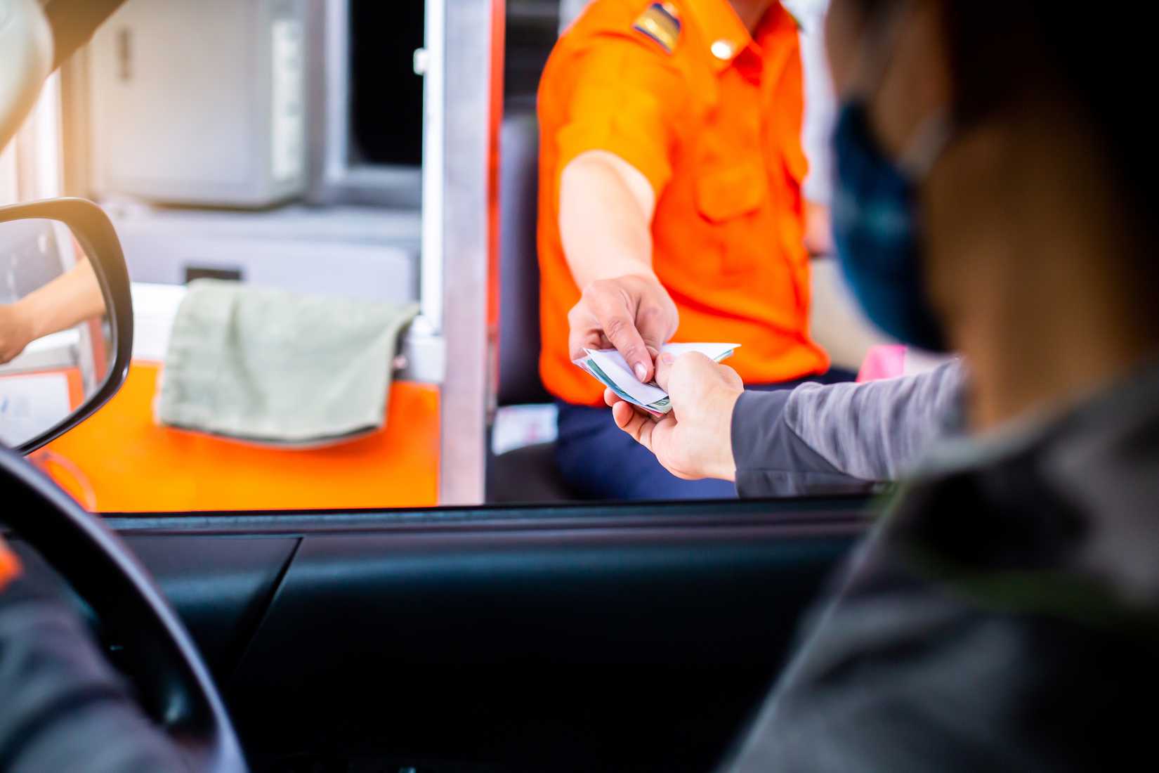 Человек оплачивает дорожный сбор на пункте оплаты