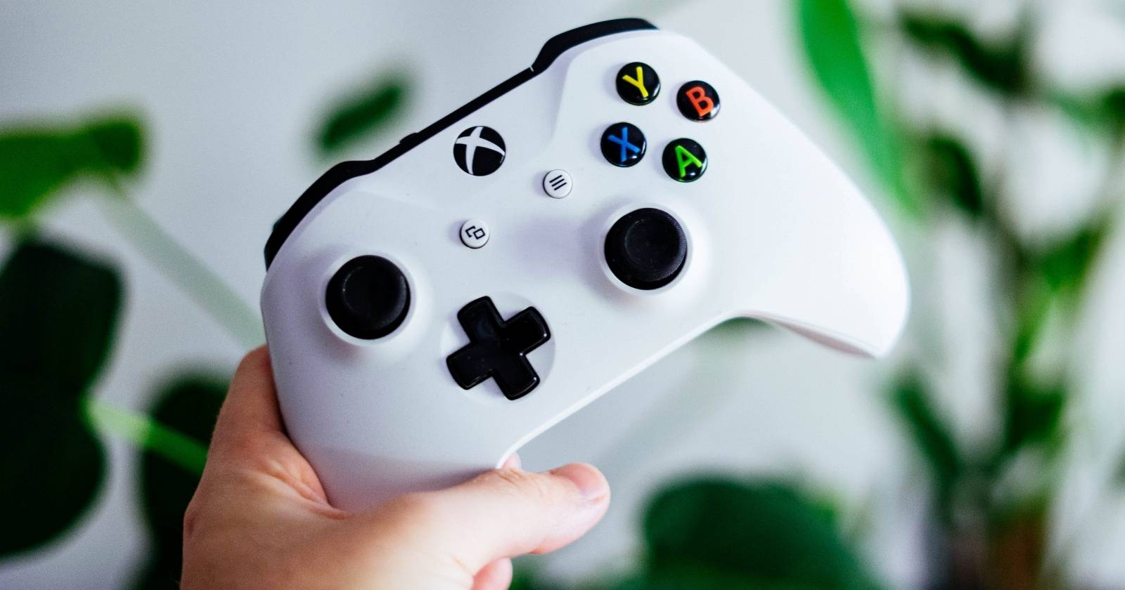 Фотография человека, держащего белый контроллер Xbox One