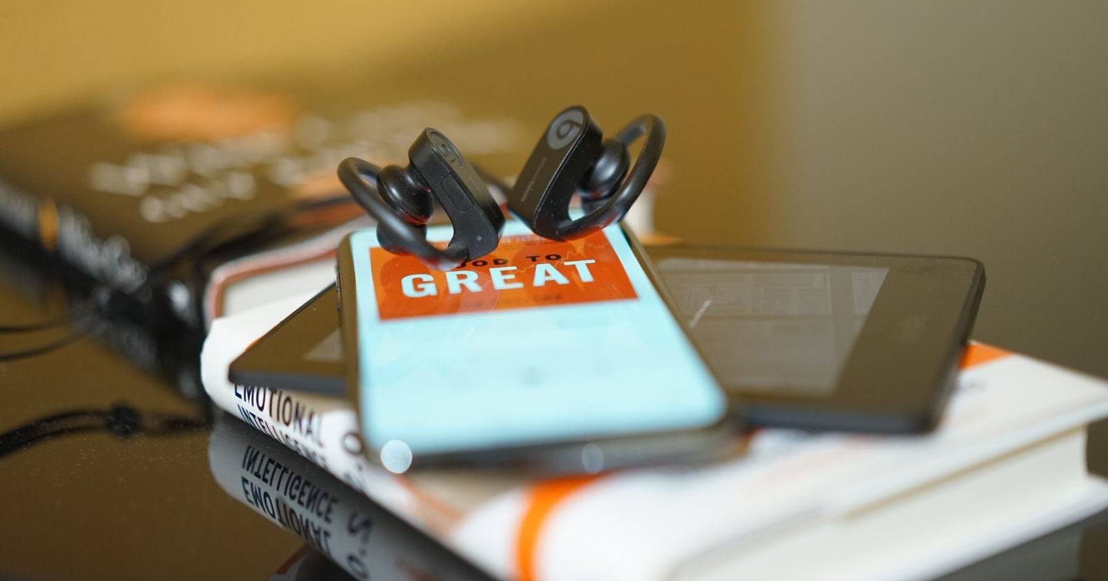 Пара полноразмерных наушников на смартфоне с открытым экраном аудиокниги