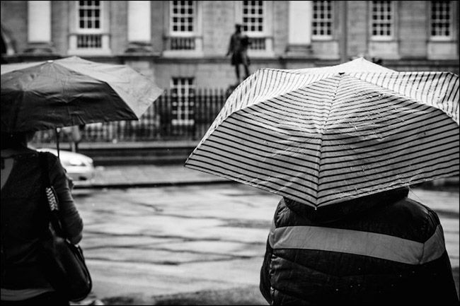 Пассажиры под зонтом на дождливой улице