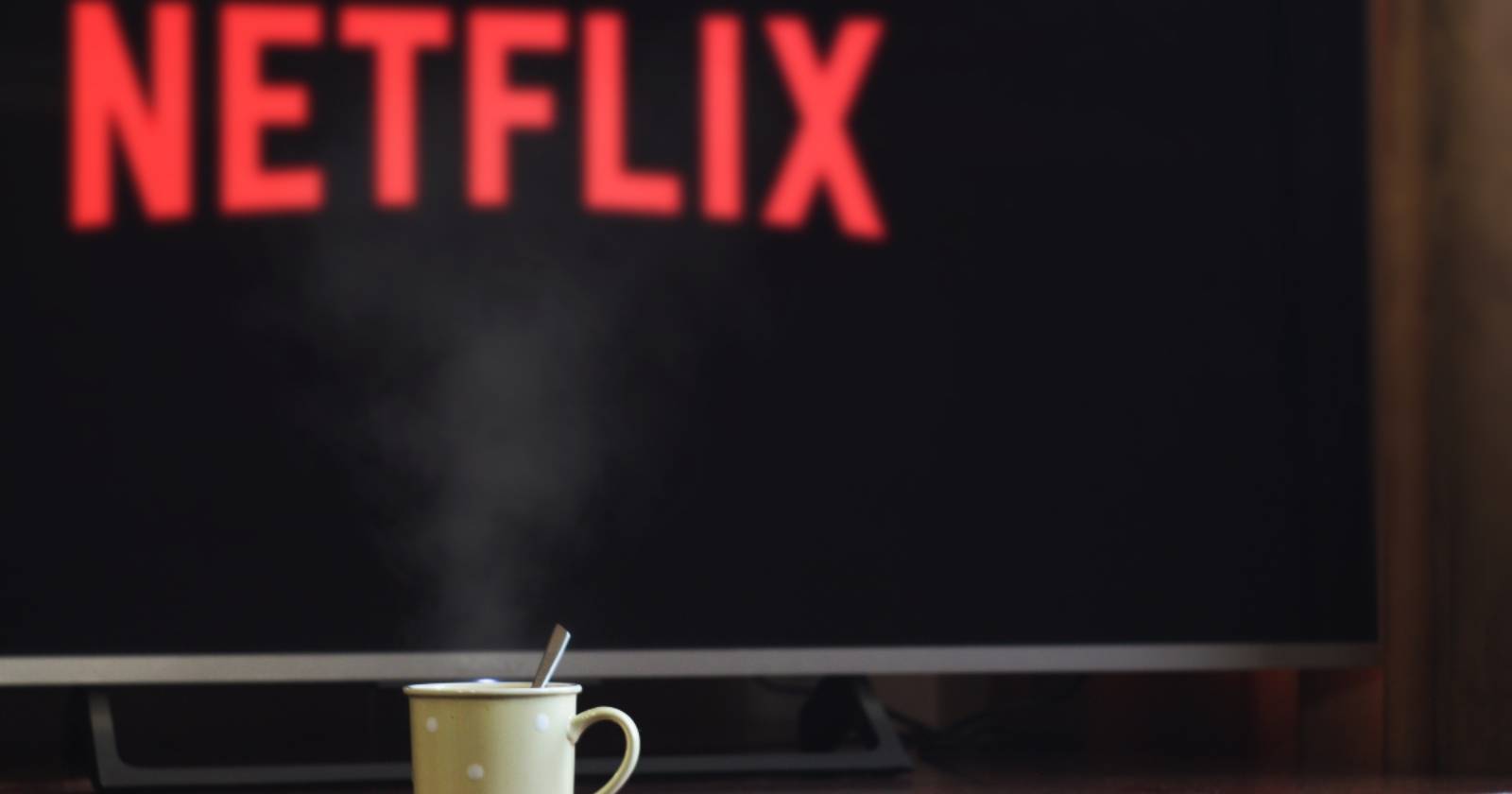 Кружка на фоне плоского телевизора с логотипом Netflix