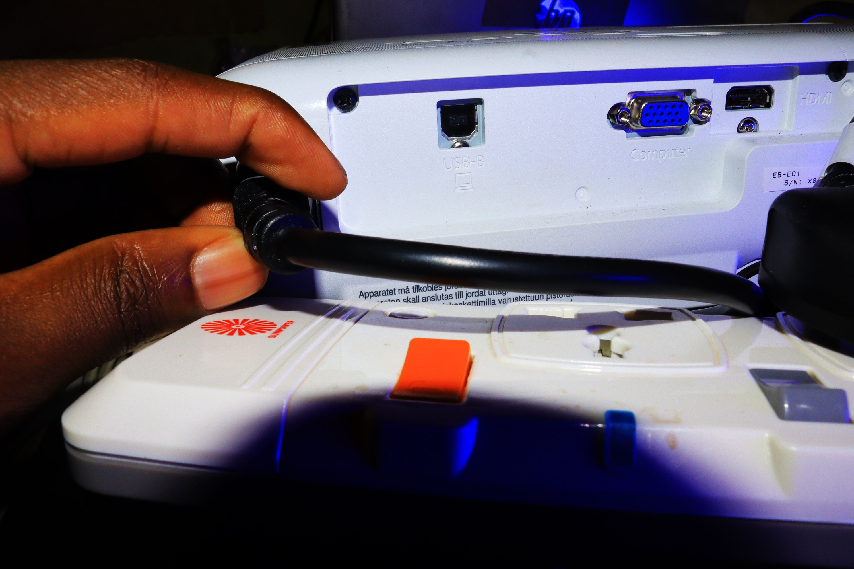 Рука человека отключает проектор от электросети