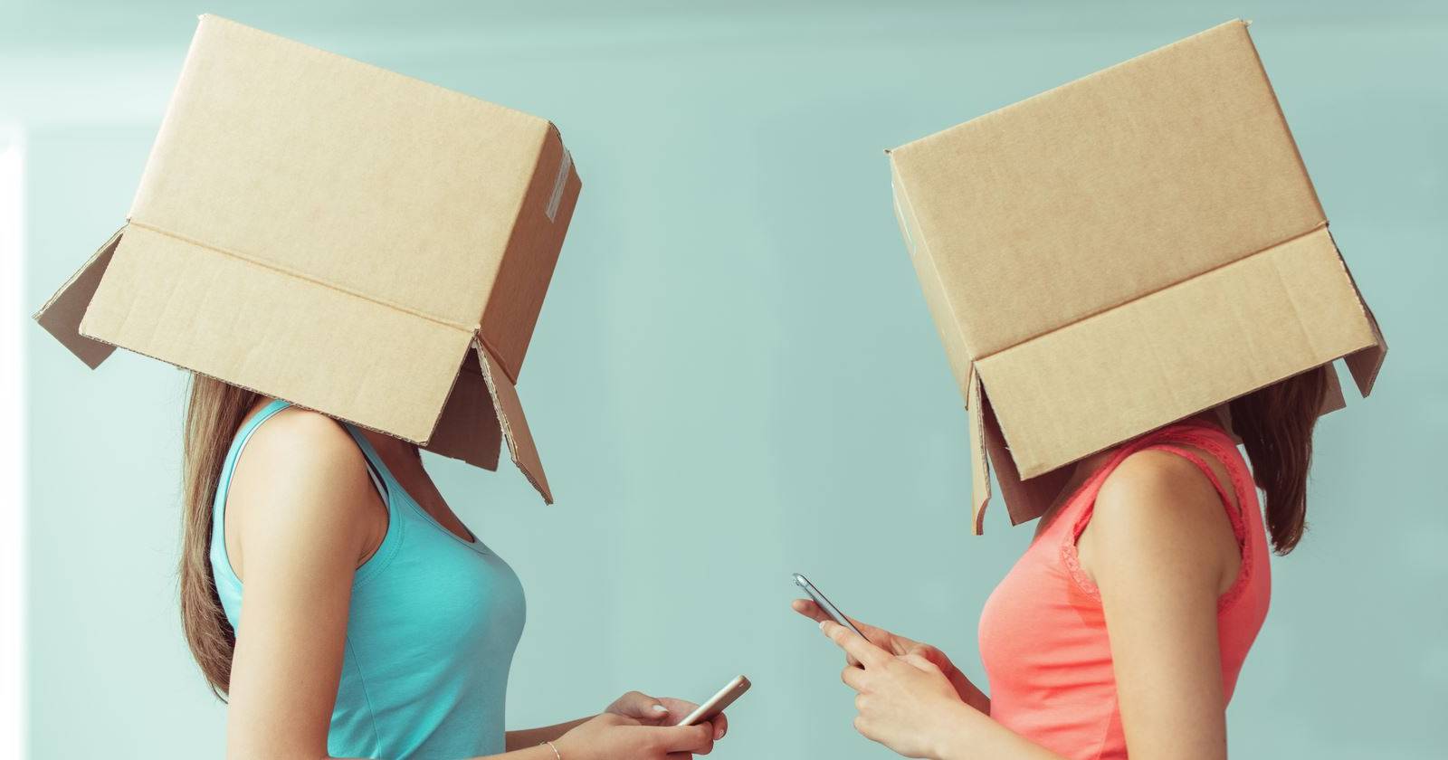 Две женщины в картонных коробках на головах пользуются смартфонами