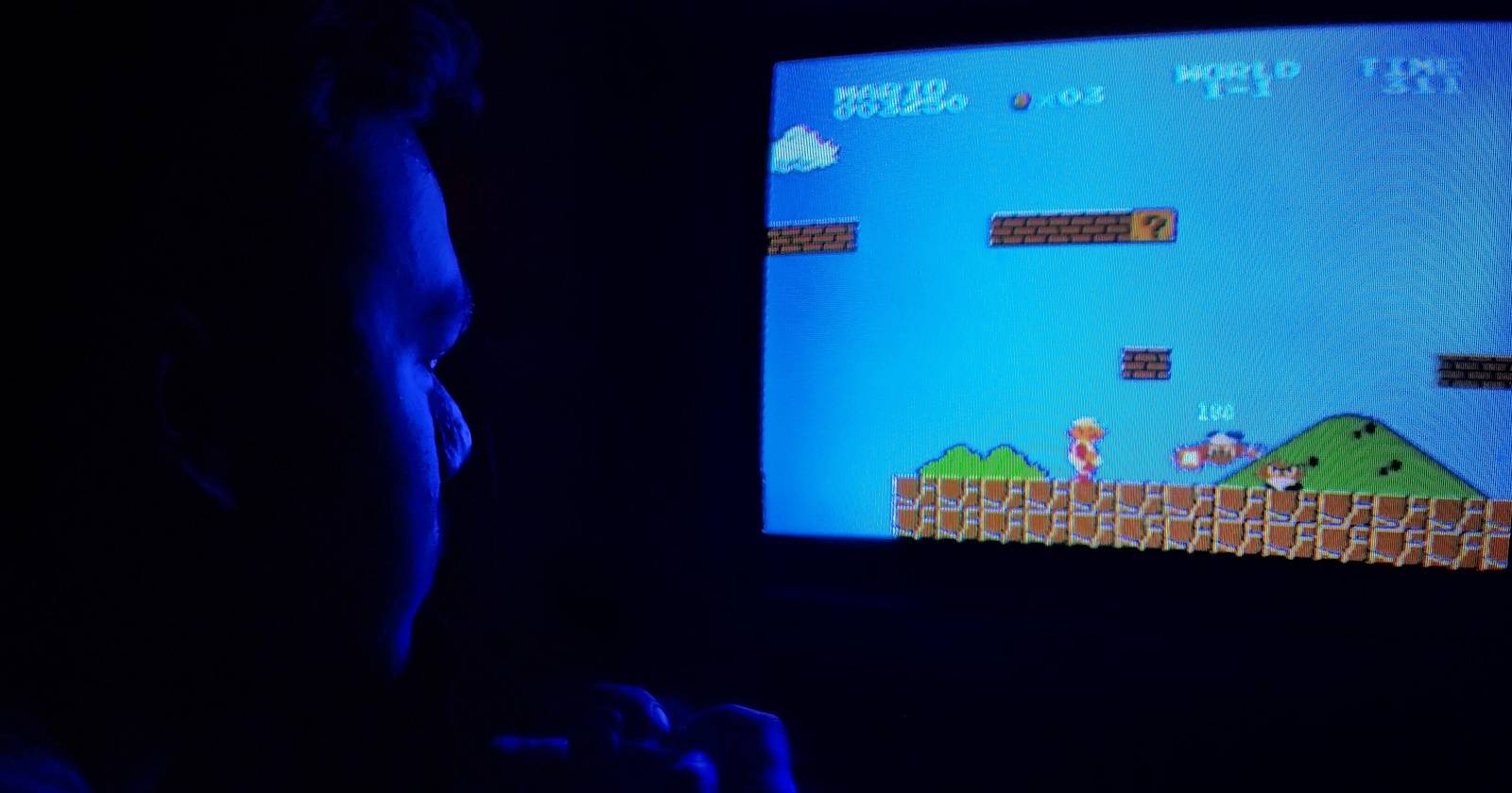 Человек играет в Super Mario Bros. с контроллером