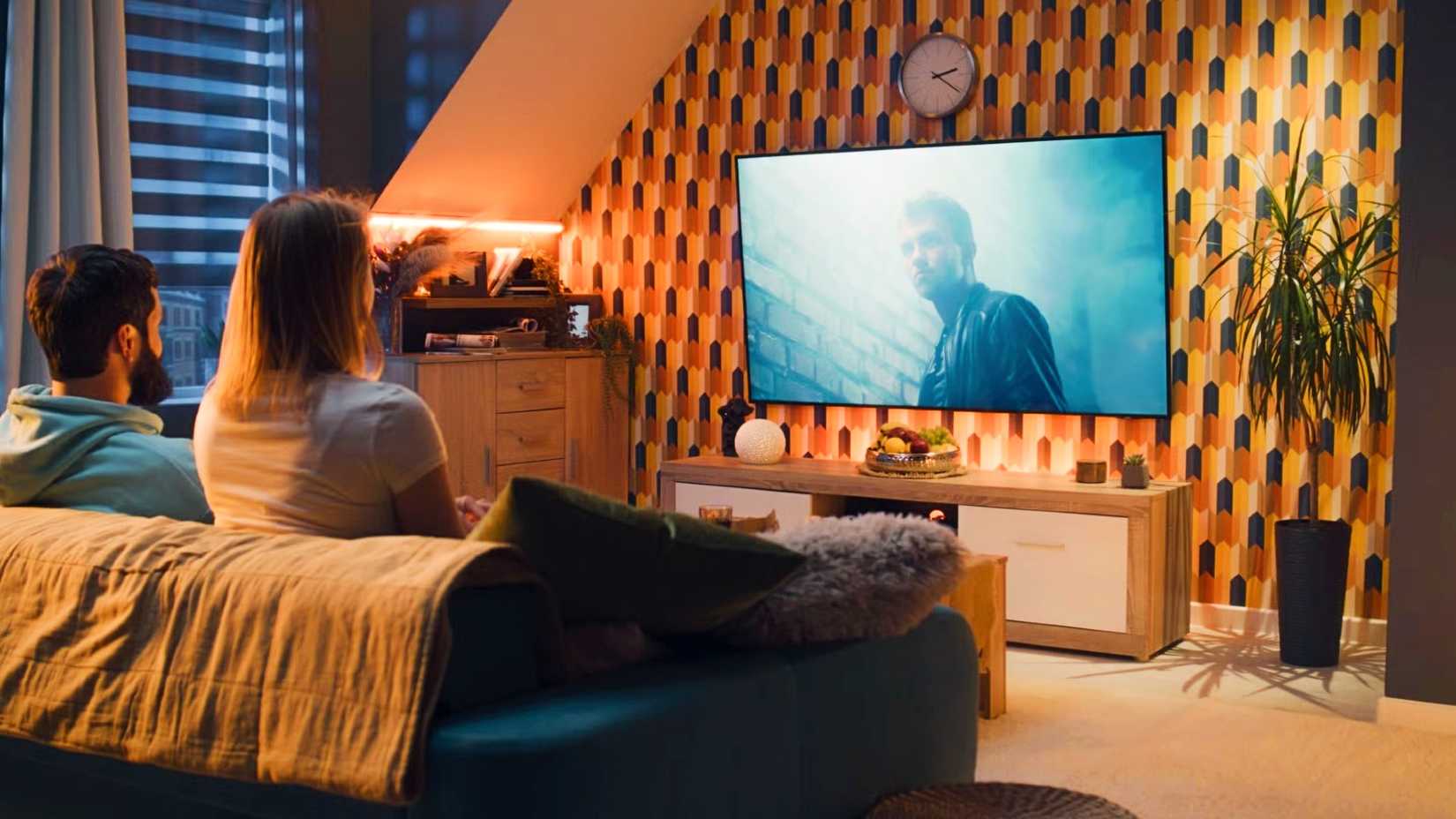 A couple sitting on a couch and watching a movie.