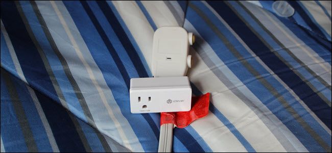 Умный штекер iClever, подключённый к вилке кондиционера, лежит на синем покрывале
