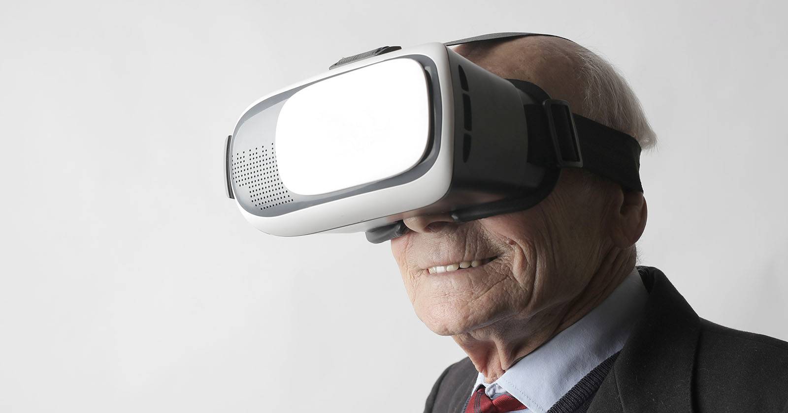 Пожилой человек в VR-гарнитуре, улыбается и взаимодействует с окружением