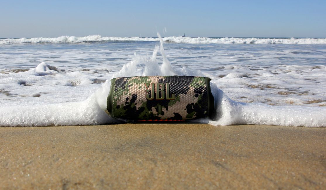 The JBL Charge 5 speaker on a beach.