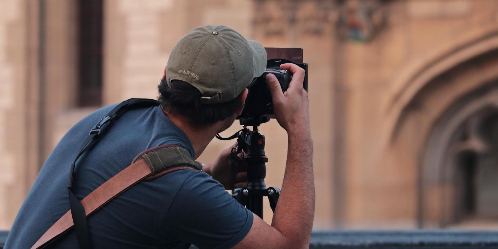 A man on a rooftop photographing a building