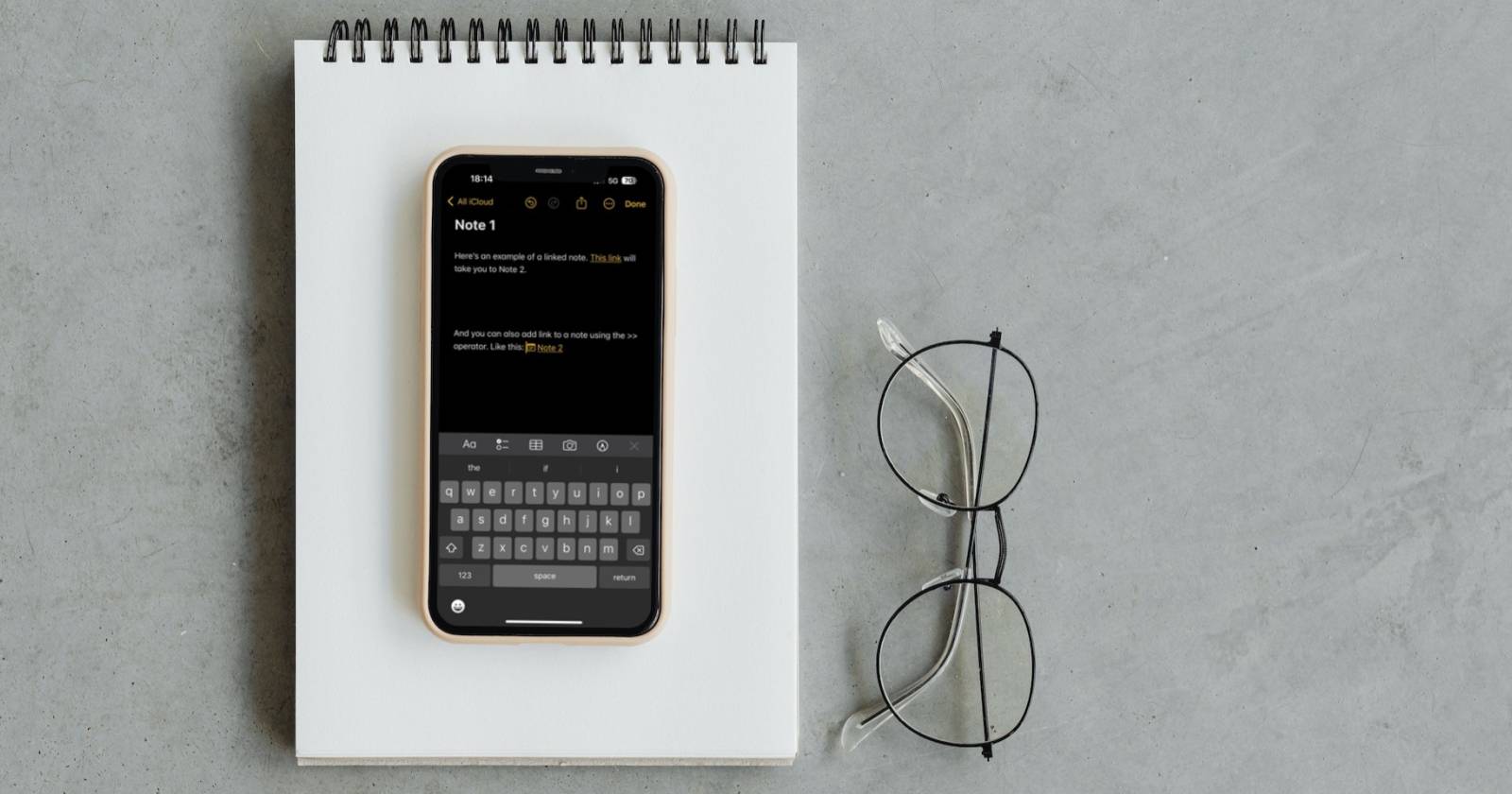 iPhone на блокноте с открытым приложением «Заметки»
