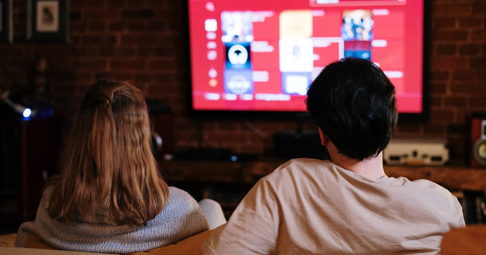 Мужчина и женщина сидят на диване перед телевизором