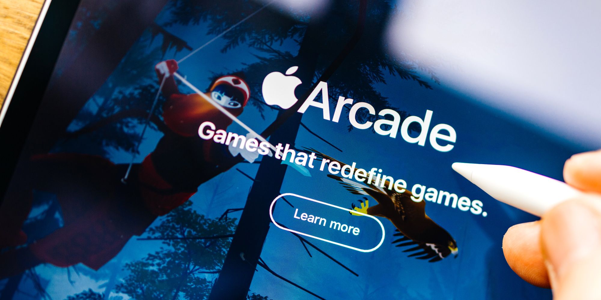 Логотип Apple Arcade на экране планшета со стилусом.