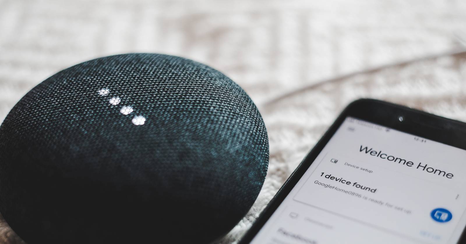 чёрный Google Nest Mini рядом со смартфоном