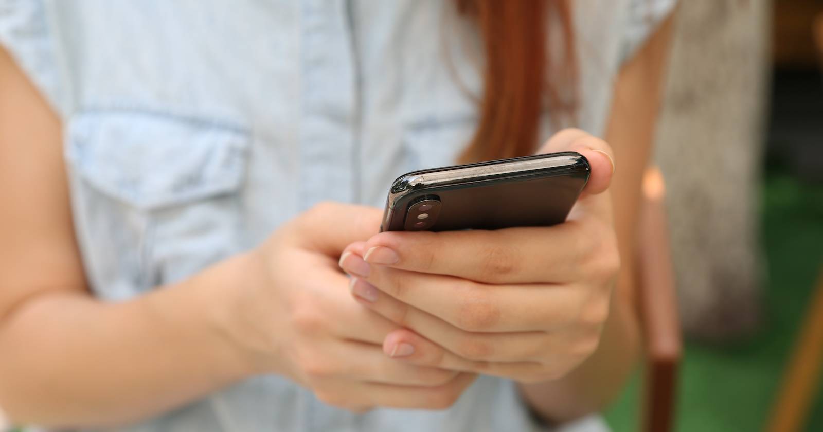 Женщина держит и использует чёрный смартфон
