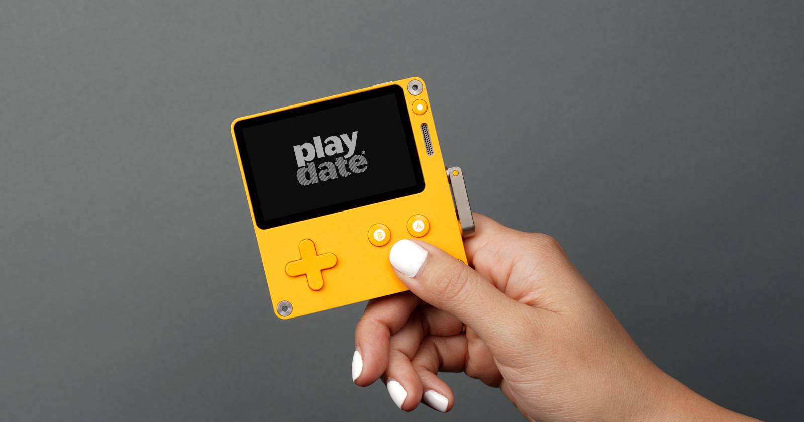Портативная консоль Playdate в руке, вид спереди и сбоку