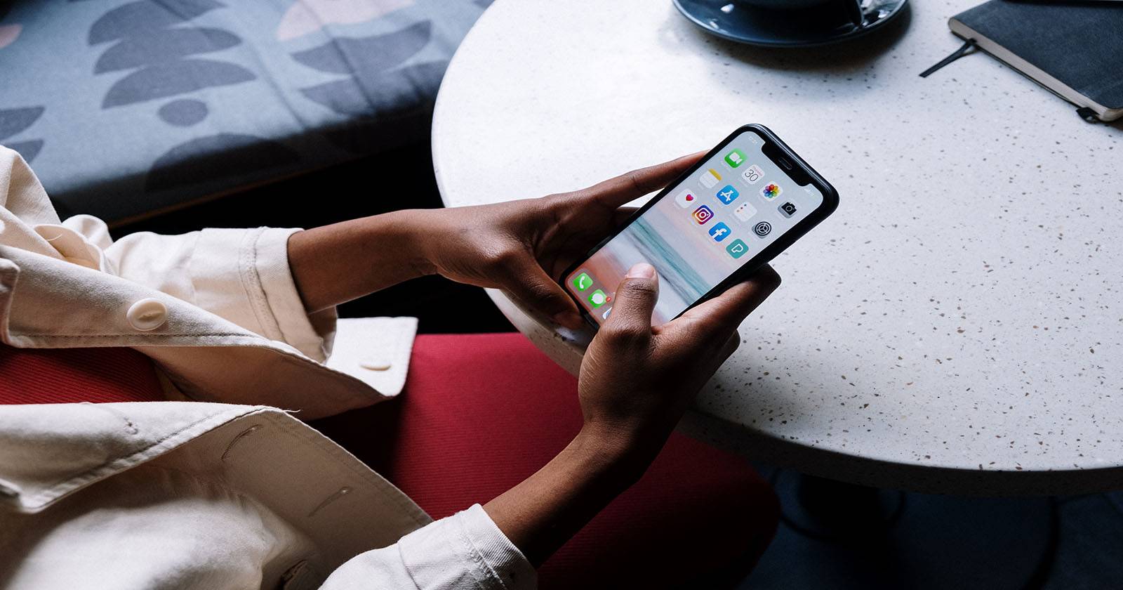 женщина сидит за столом и пользуется iPhone
