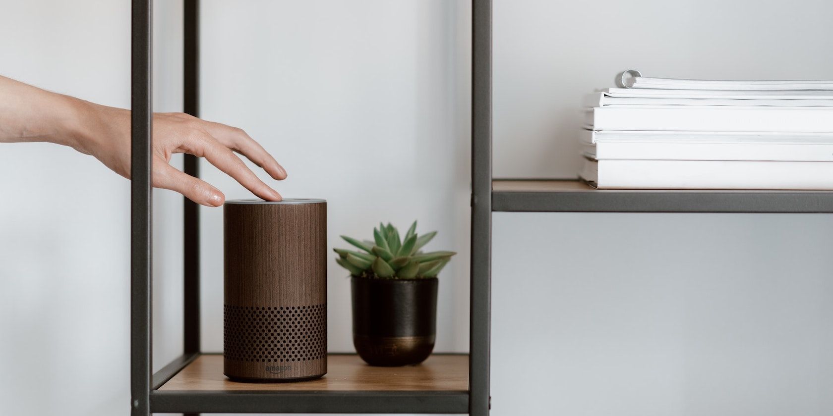 Рука прикасается к устройству Amazon Echo