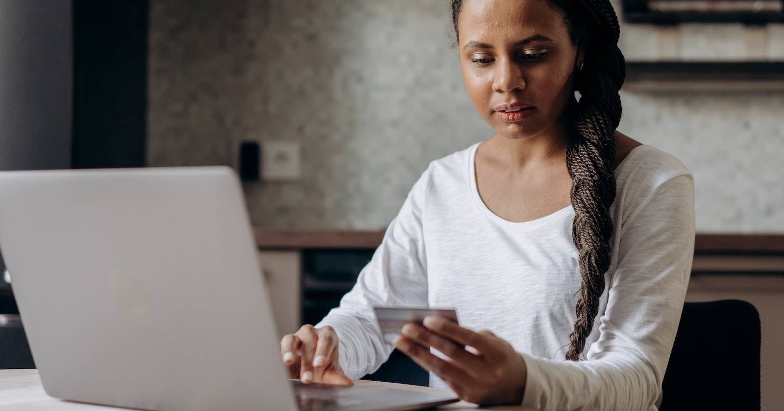 Женщина держит кредитную карту и вводит данные на ноутбуке