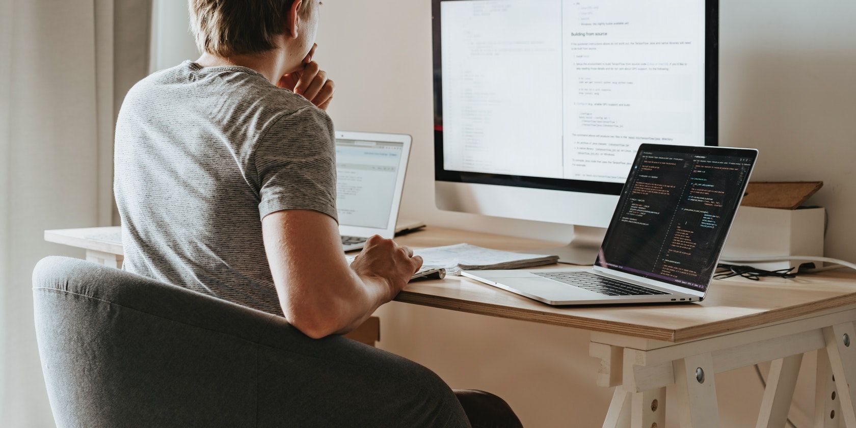 A man writing code on three screens