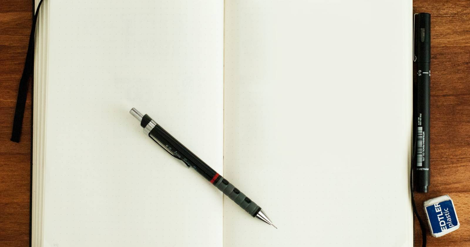 Mechanical Pencil Pen and Eraser on Blank Notebook