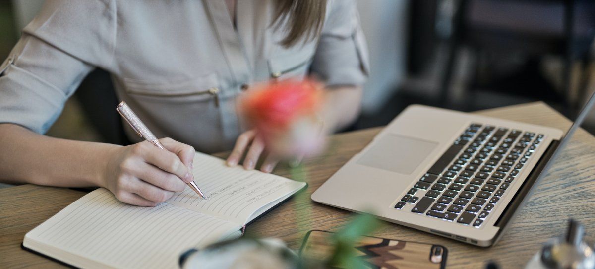 Человек делает заметки с ноутбуком на столе