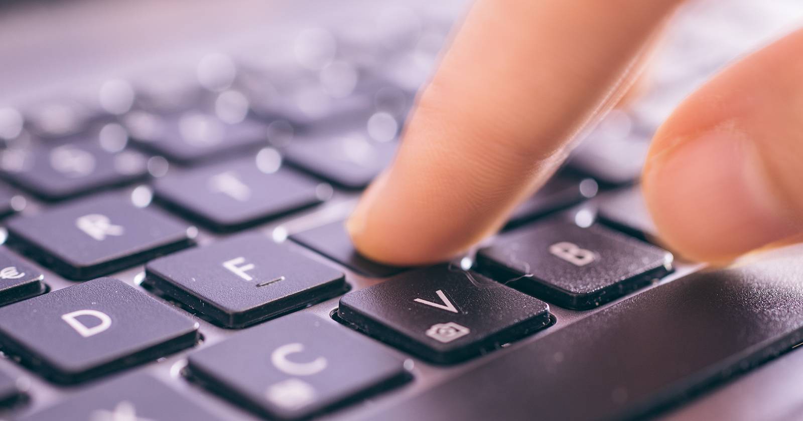 Крупный план руки на клавиатуре с подсветкой и пальцем над клавишей