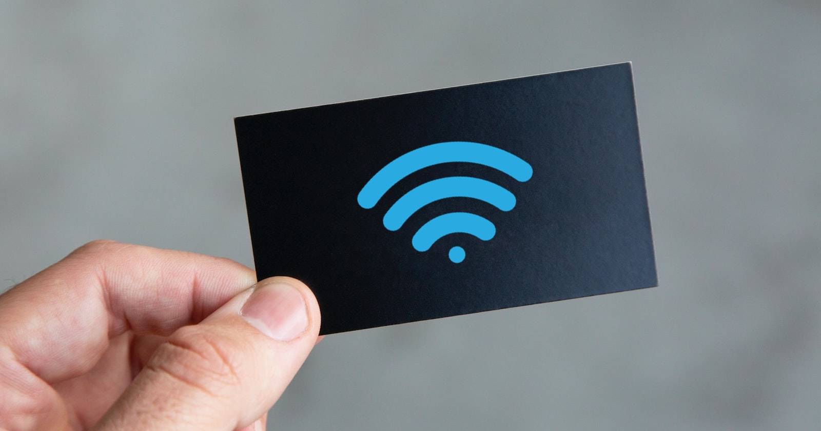 Рука держит чёрную визитку с синим символом беспроводной связи.