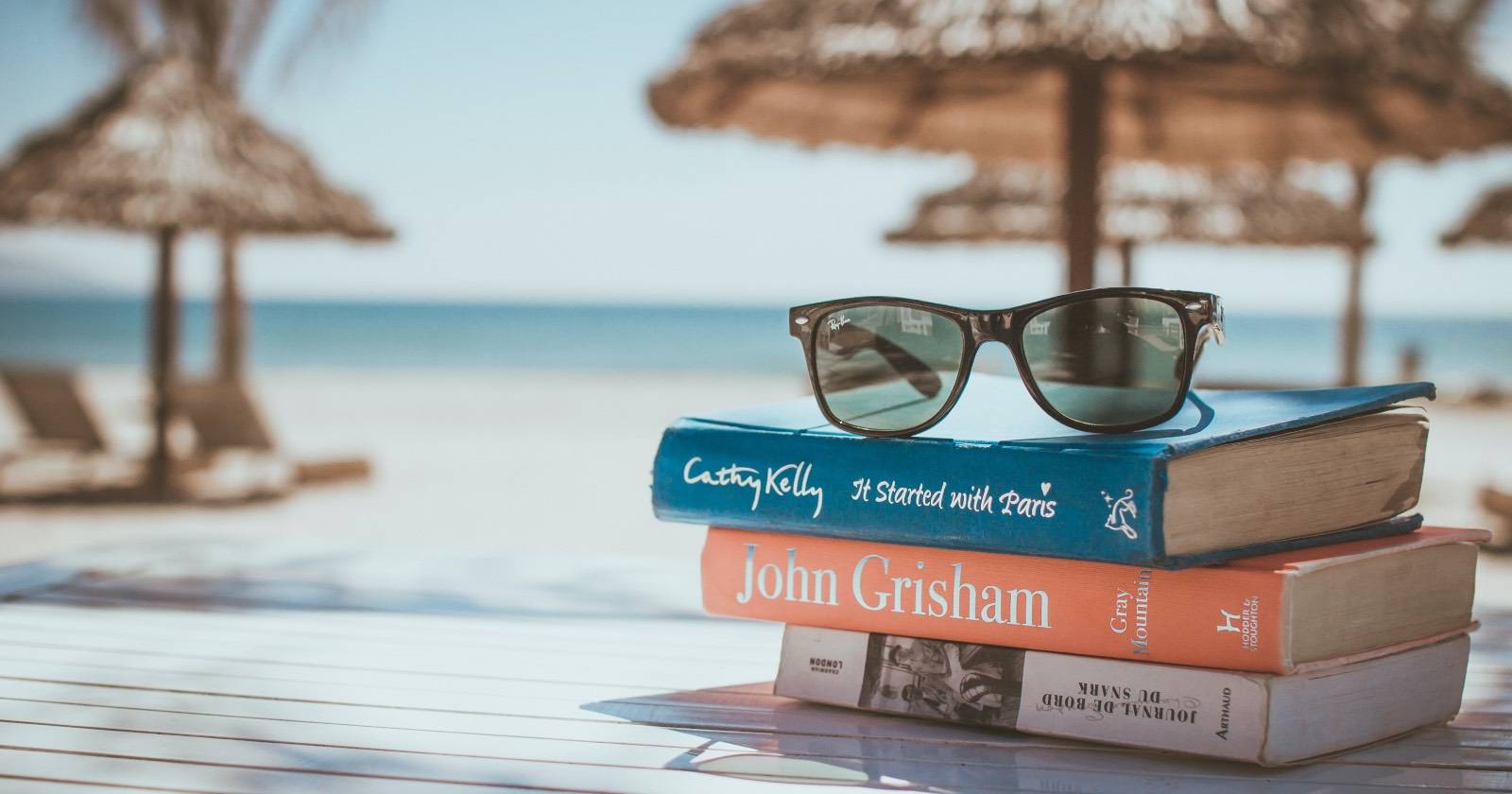 Книги на пляже в сумке рядом с ноутбуком