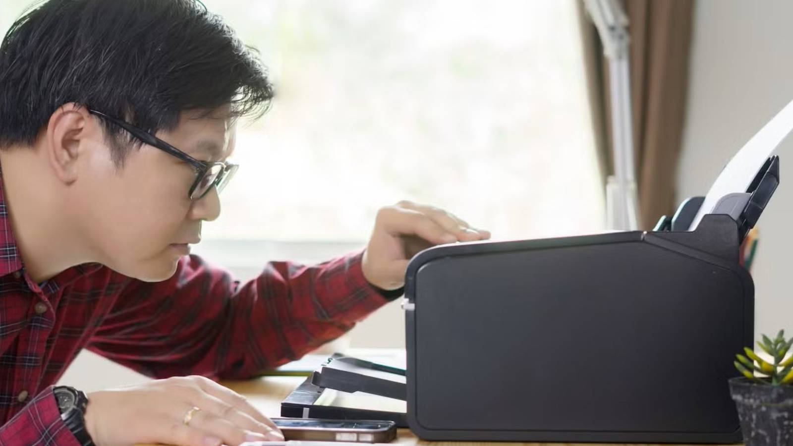 Мужчина смотрит на принтер на рабочем столе.