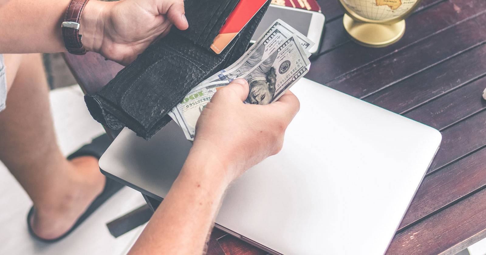 Подержанный ноутбук на деревянном столе, вид сверху, рядом блок питания и кабели